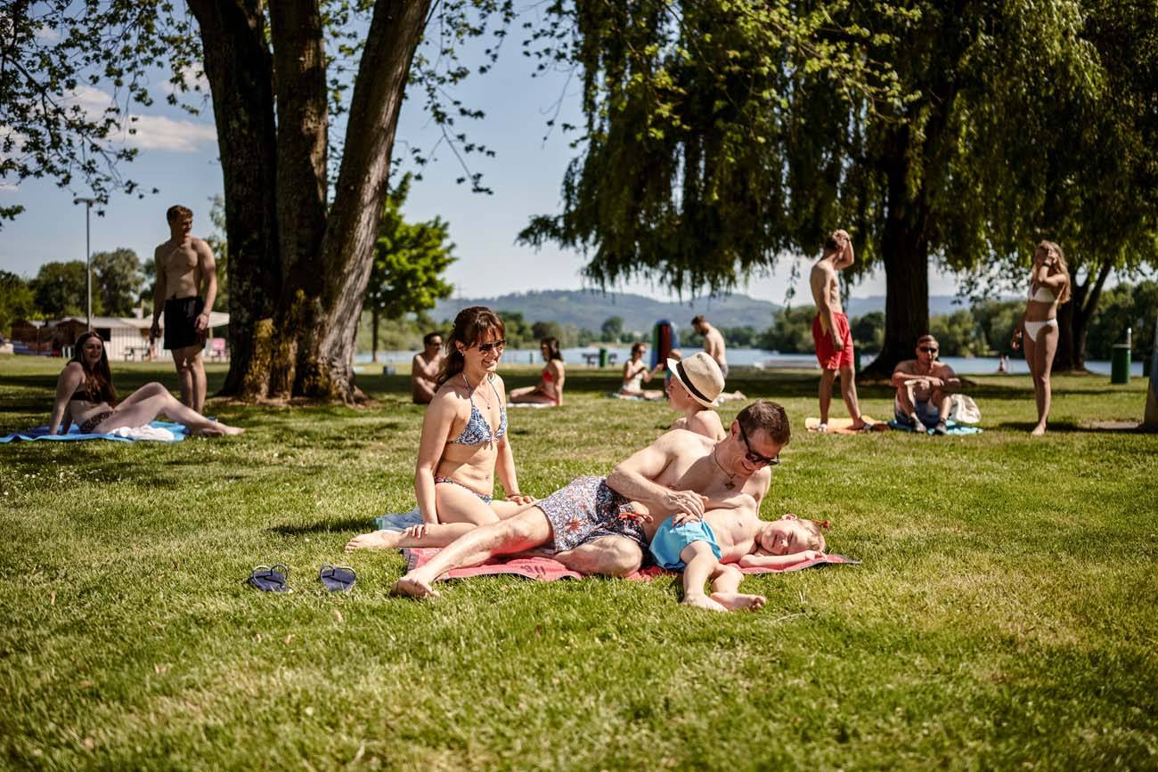 Des parents avec leur enfant sont allongés sur une serviette à la plage.